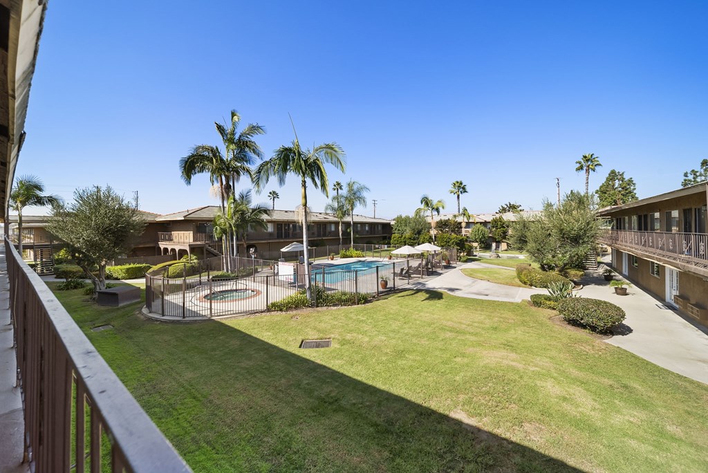 A view of a pool and palm trees from a balcony.