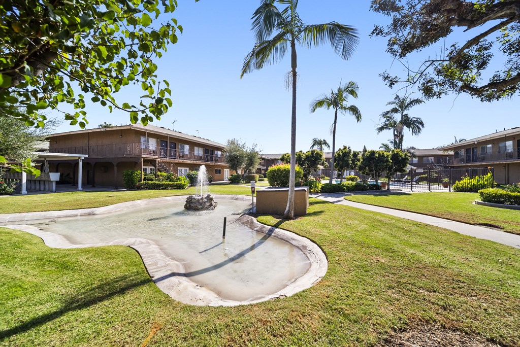 A playground with a slide in the middle of a grassy area.