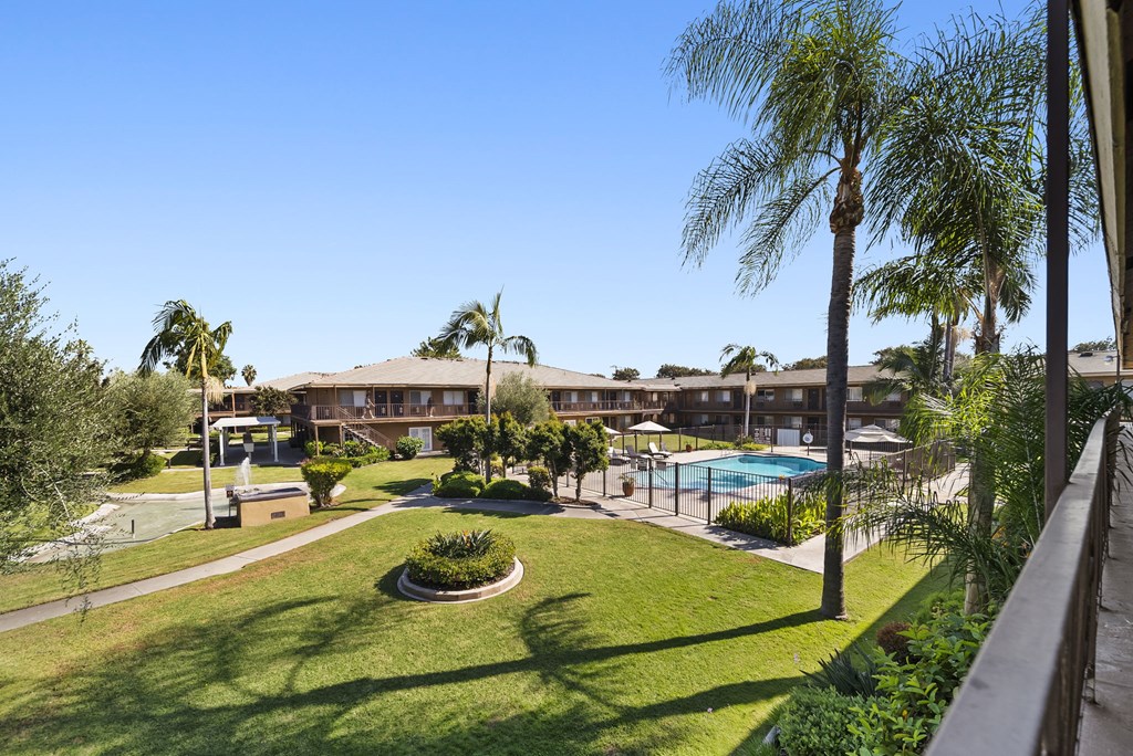 A view of a pool and a building from a balcony.