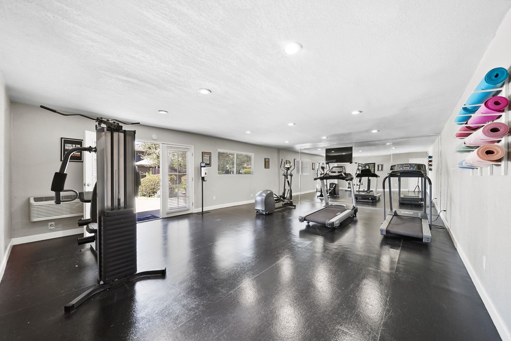 A gym with a variety of equipment including treadmills, weights, and exercise machines.