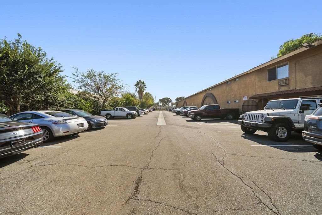 A parking lot with cars parked on both sides of the street.