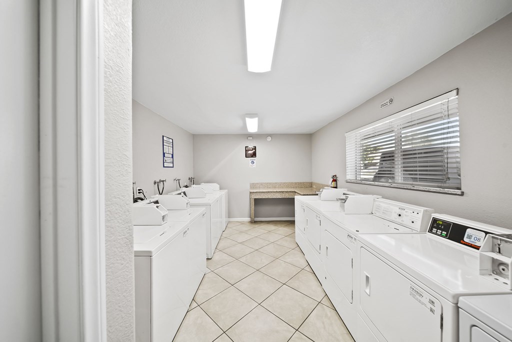 A laundry room with a washer and dryer on the right and a sink on the left.