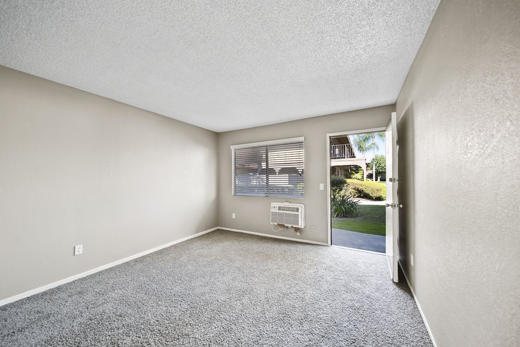 A room with a carpeted floor and a door leading outside.