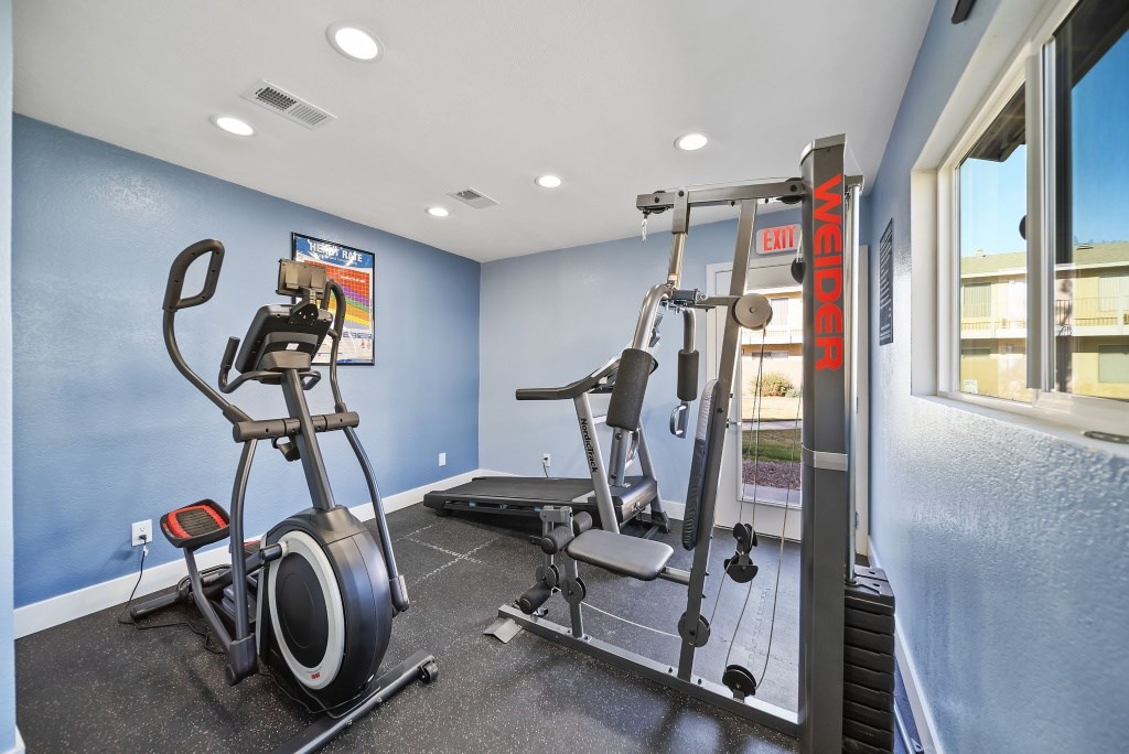 A gym room with a weight machine and a stationary bike.