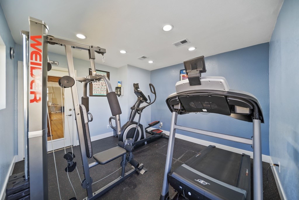A gym with a treadmill, a stationary bike, and a weight machine.