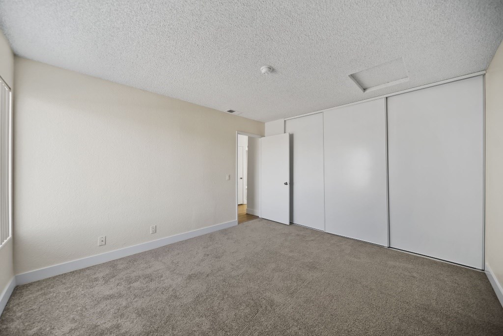 A room with white walls and carpeted floor with a door on the right.