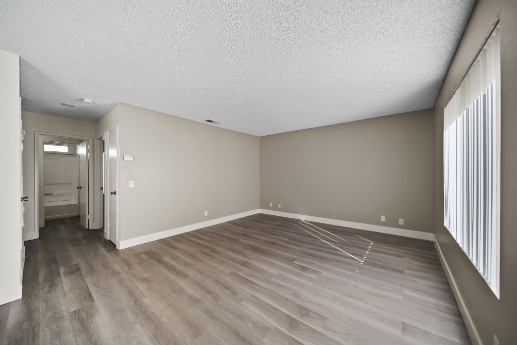 A room with wooden flooring and a doorway leading to another room.
