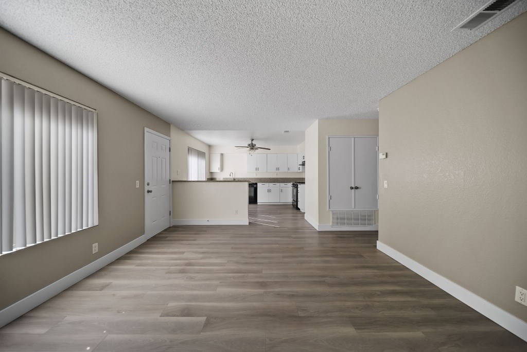 A spacious room with wooden flooring and white walls.