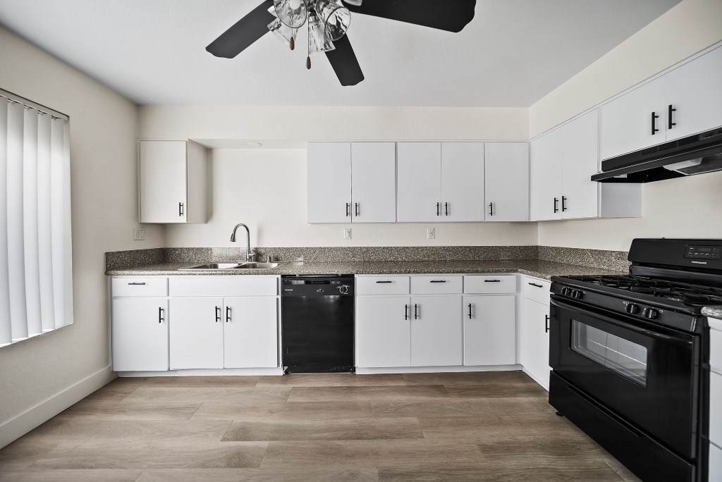 A kitchen with black appliances and white cabinets.