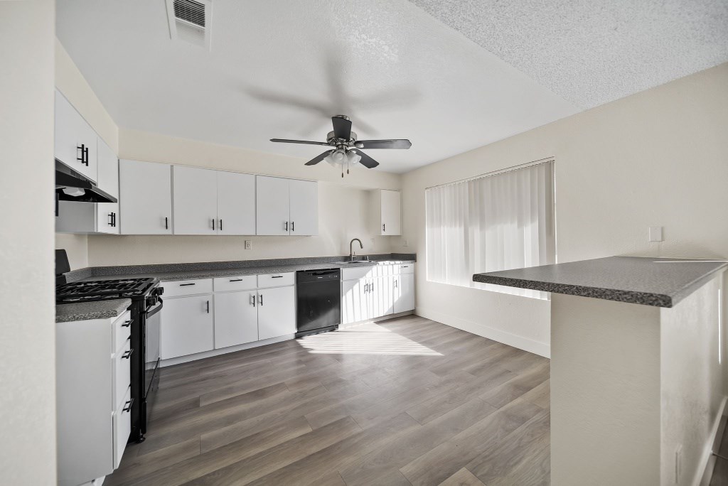A kitchen with a fan and wooden floors.