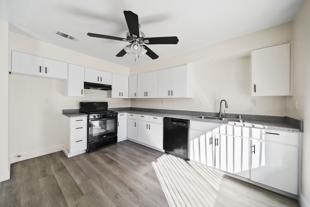 A modern kitchen with white cabinets and a black stove top oven.