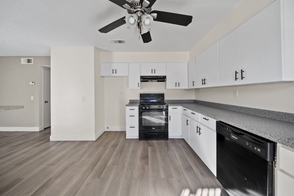 A modern kitchen with a black oven and white cabinets.
