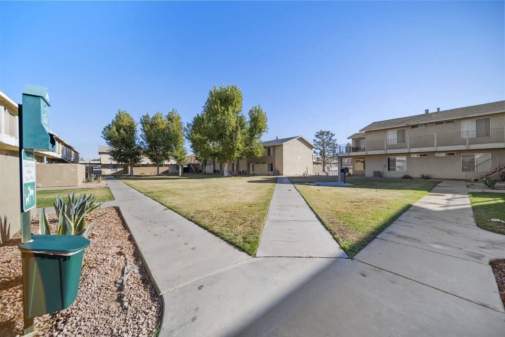 A sunny day in a residential area with apartment buildings and a sidewalk.