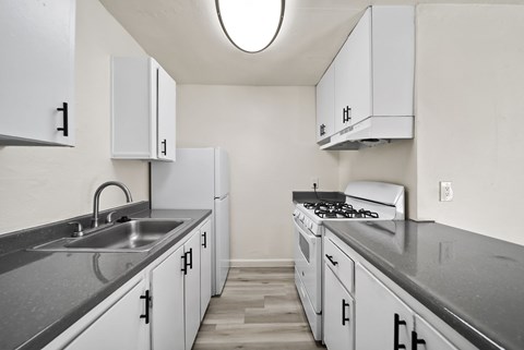 A kitchen with white cabinets and a stove top oven.