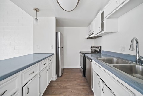 A kitchen with white cabinets and a wooden floor.