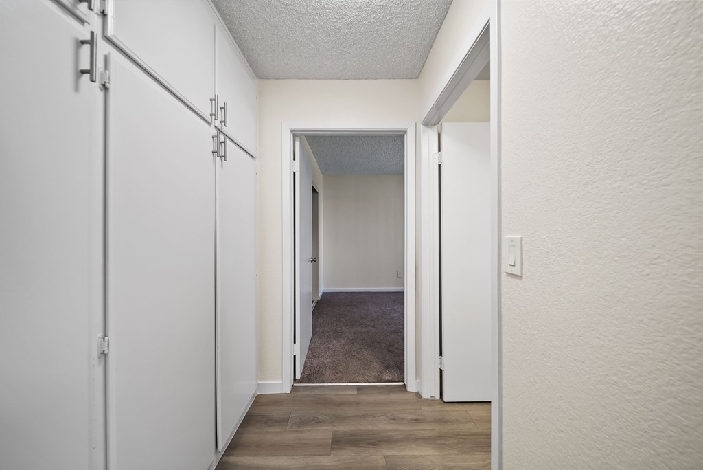 A hallway with white walls and a grey carpet.