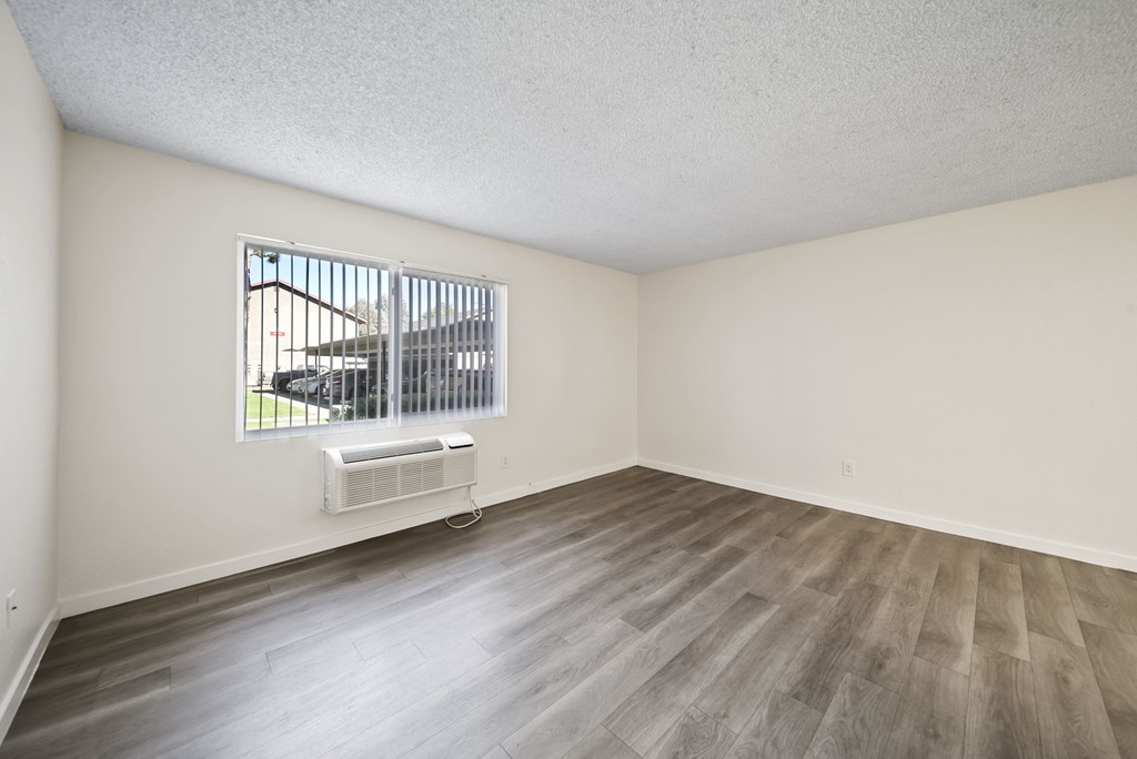 A room with a window and a fan on the floor.