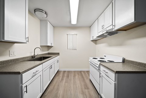 A kitchen with white cabinets and a granite countertop.