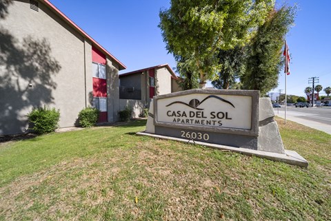 A sign for Casa Del Sol Apartments stands in front of a building.