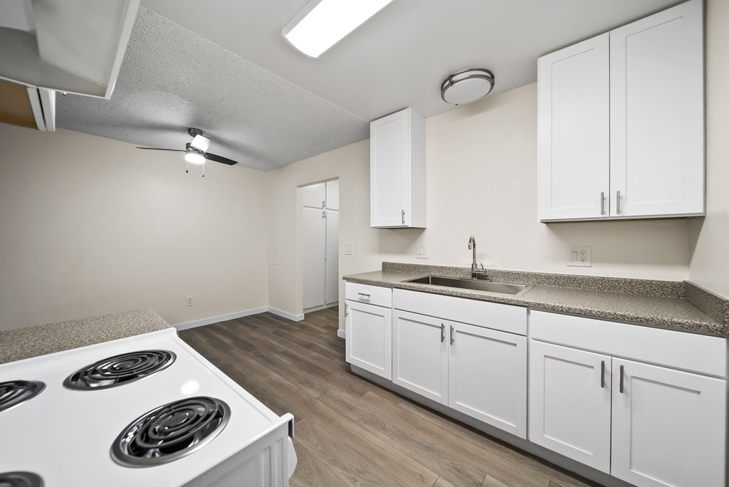 A kitchen with white cabinets and a stove top oven.