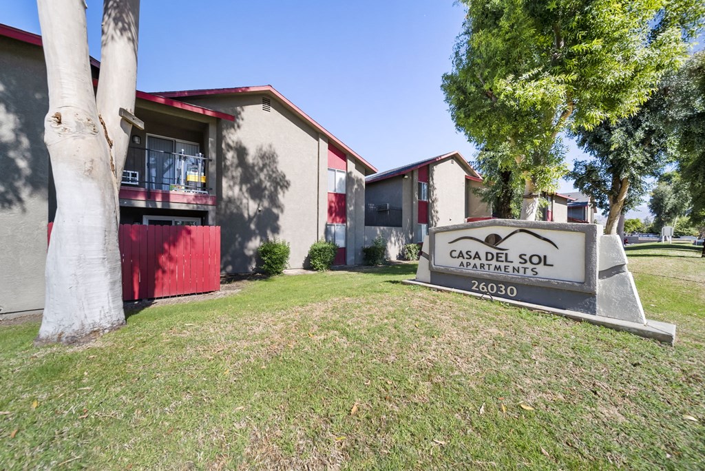 A sign for Casa Del Sol Apartments stands in front of a building.