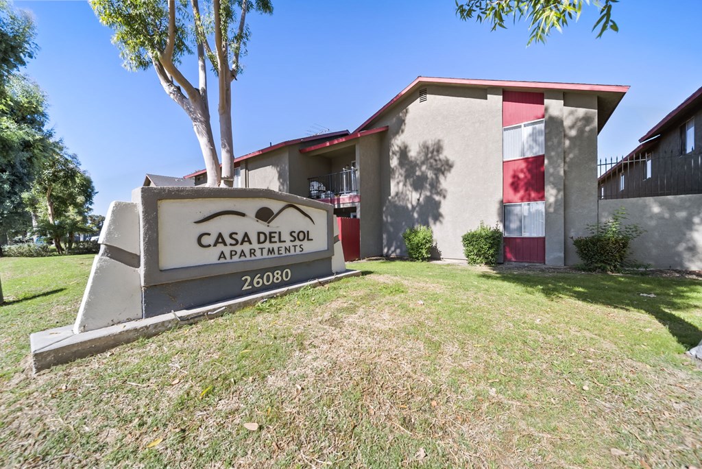 A sign for Casa Del Sol Apartments stands in front of a building.