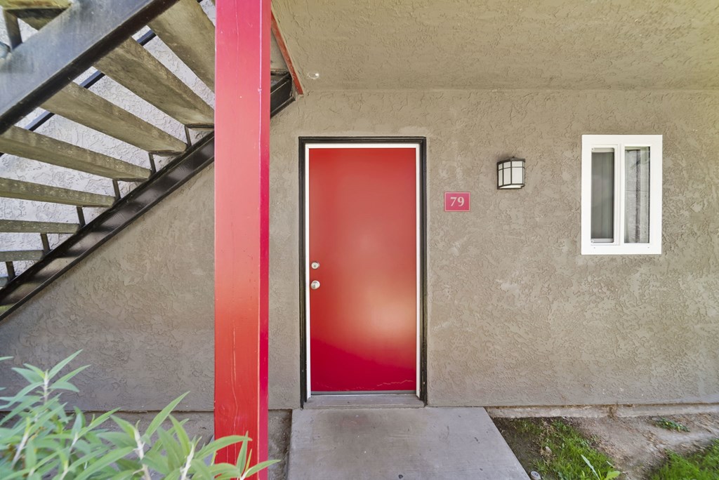A red door with a number 79 on the wall above it.
