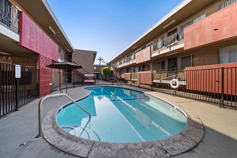 A small pool in a courtyard surrounded by a black fence.