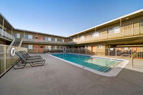 A pool area with sun loungers and a fence.