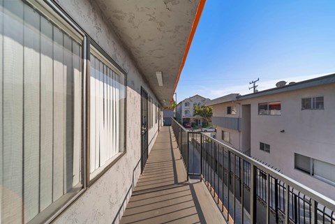 A long balcony with a black railing and a white wall.