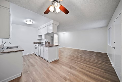 A kitchen with white cabinets and a wooden floor.
