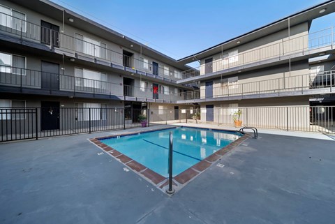 A swimming pool in the middle of a courtyard surrounded by apartment buildings.