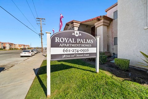 A sign for Royal Palms Apartment Homes stands in front of a building.