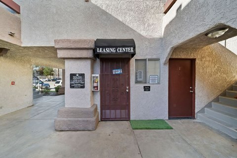 The leasing center has a brown door and a green mat on the steps.