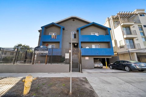 A blue and beige two-story apartment building with a basketball hoop on the first floor.