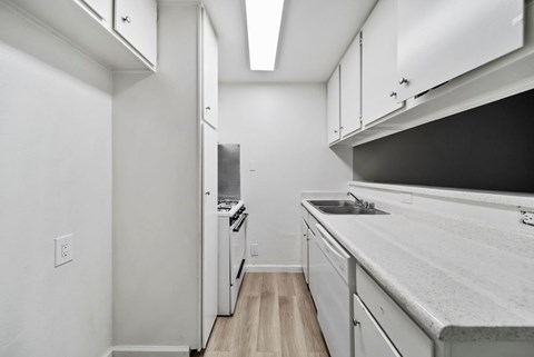 A kitchen with white cabinets and a black counter top.