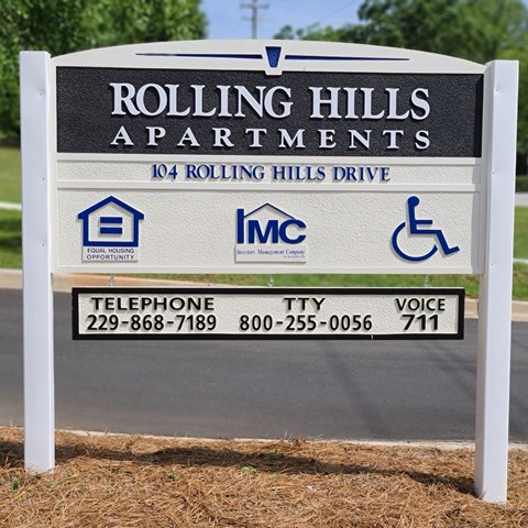 A sign for Rolling Hills Apartments with contact information and logos.