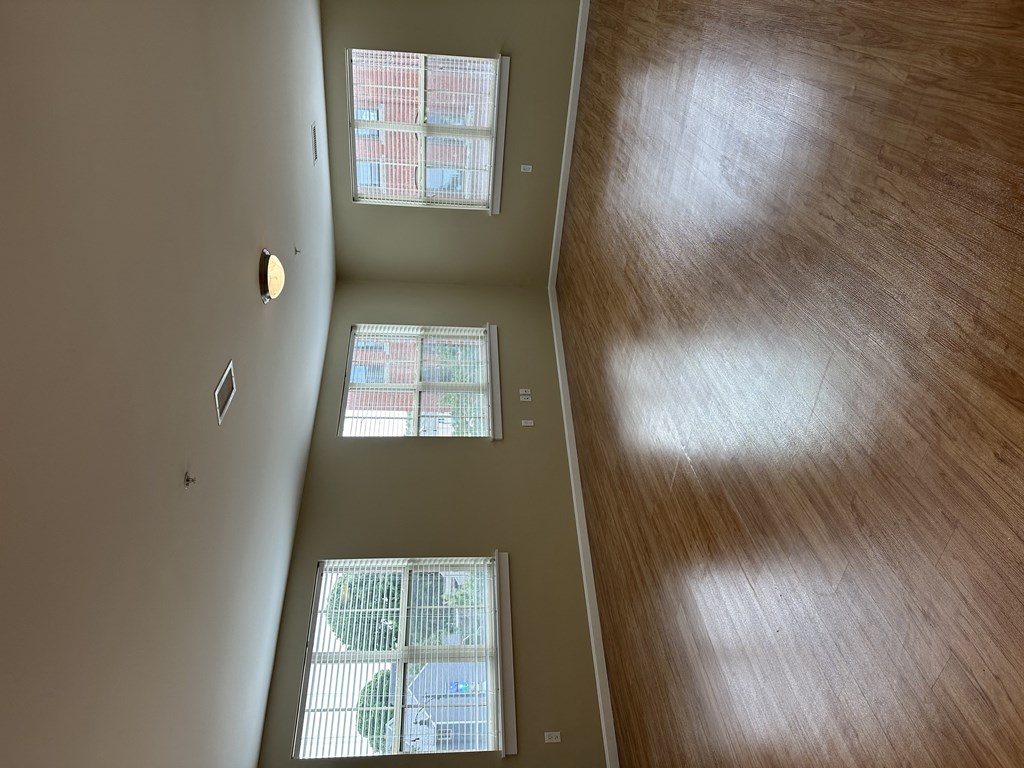 an empty room with three windows and a wooden floor