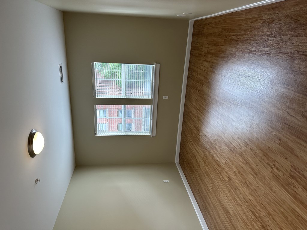 an empty room with a window and a wooden wall