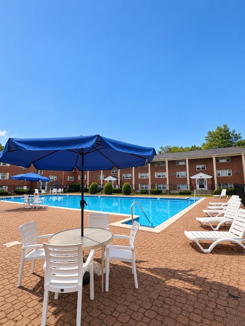 A blue umbrella is over a table with chairs around it.