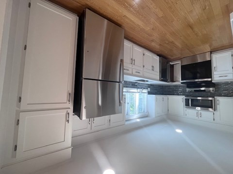 A kitchen with white cabinets and a wooden ceiling.