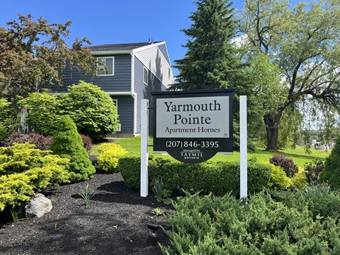 a sign for yarmouth pointe apartment homes in front of a garden