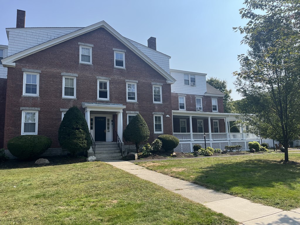 a red brick house with a white porch and a lawn