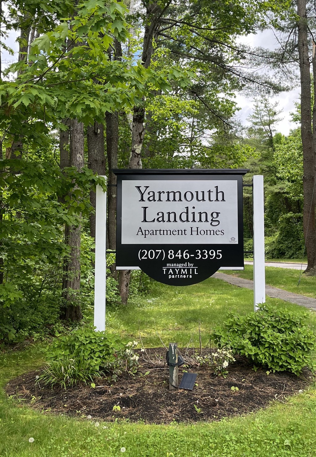 a sign for yarmouth landing apartment homes in front of trees