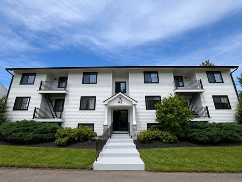 A white two-story building with black railings and a black awning.