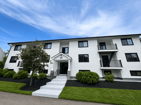 A white two-story building with black railings and windows.