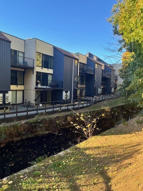 A row of modern buildings with balconies overlook a canal.