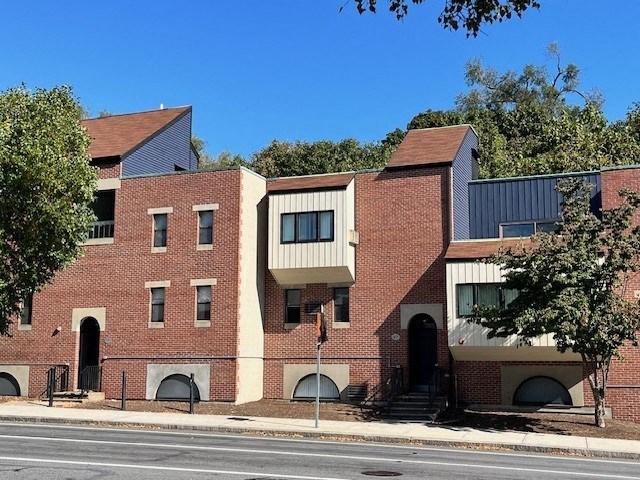 A red brick building with a black roof and a white door.