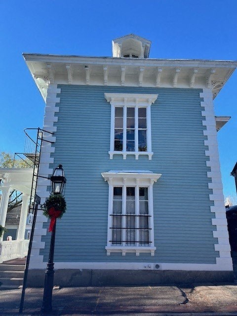 A blue house with a white window and a wreath on a black post.