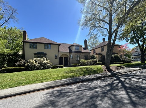 A house with a green lawn and a tree in front.